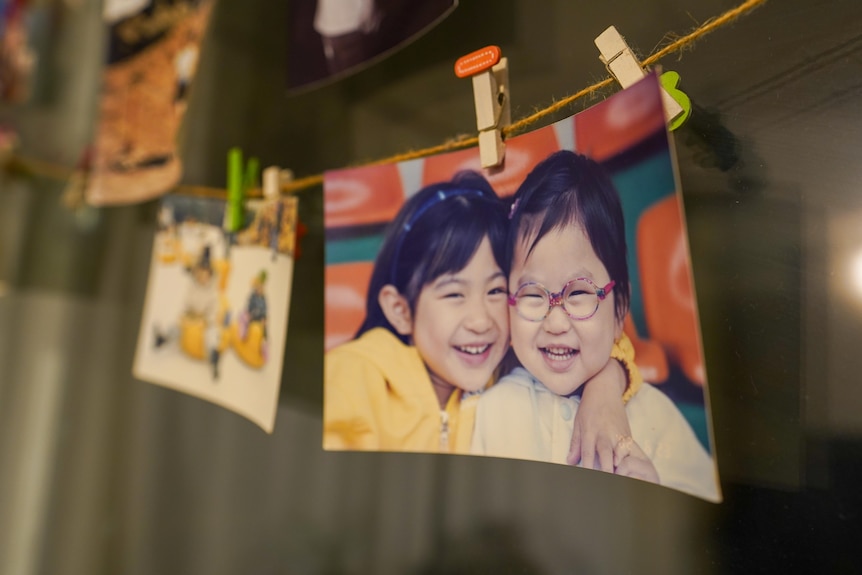Printed photos of a child hung with pegs to a piece of string 