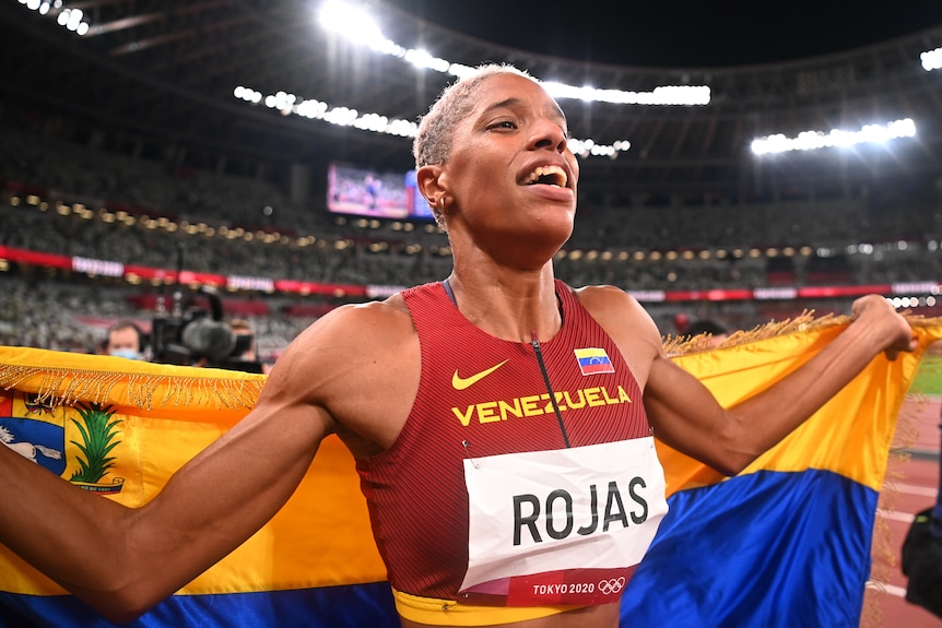 A female triple jumper from Venezuela celebrates with her national flag at the Tokyo Olympics.