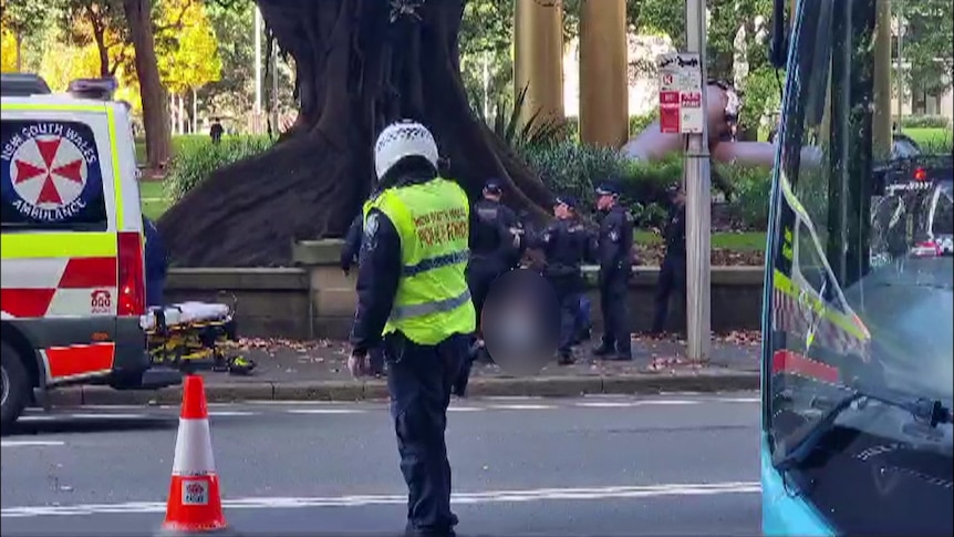 nsw police surround a man on the floor after an allaged stabbing in sydney