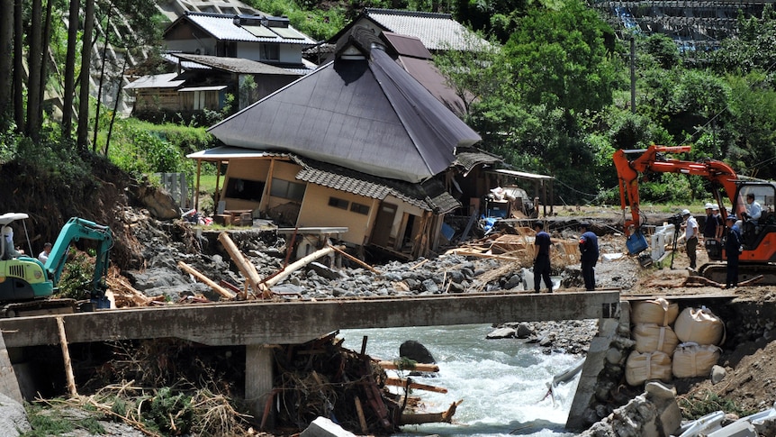 A collapsed house lies on the bank of the Mumanoue river in the city of Ukiha.
