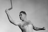 A 1930s black and white photo of an Aboriginal man shirtless and about to throw a boomerang