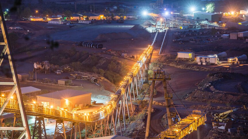 A night shot of a mine with machinery lit up by floodlights.