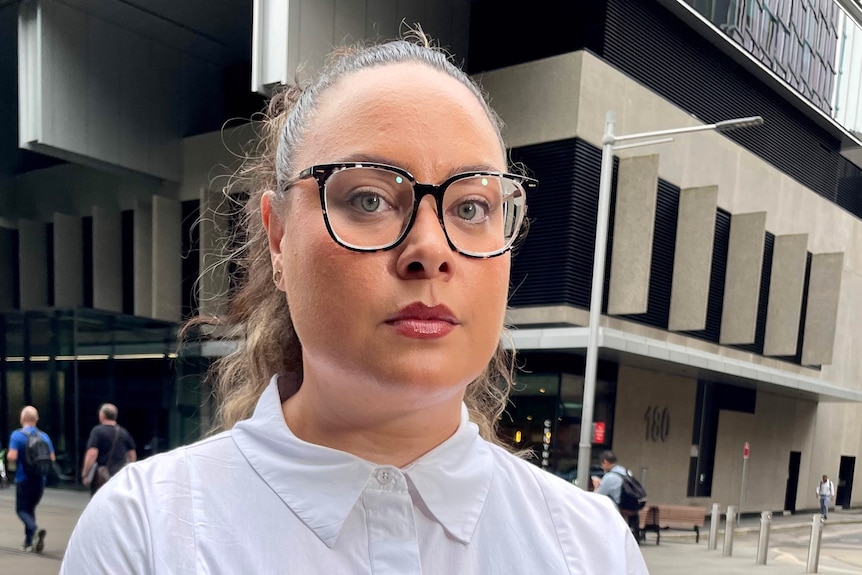 A woman looks at the camera wearing a white t-shirt in Sydney. 