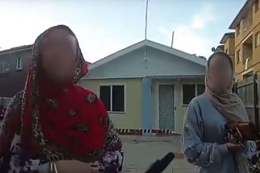 Two Afghan women appear on a police body cam, standing in front of houses.