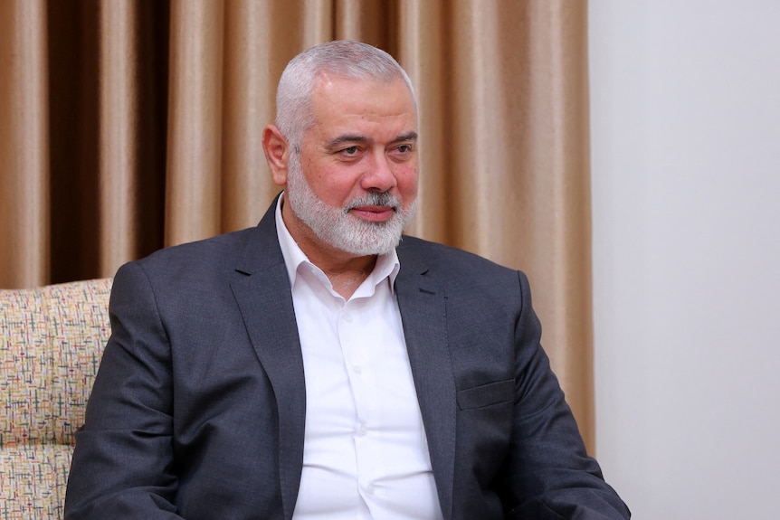Ismail Haniyeh sitting on a chair with a curtain behind him. 