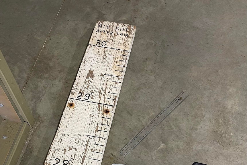 An old worn board with numbers painted on as markers for a flood