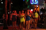 A group of young women walking down a street at night