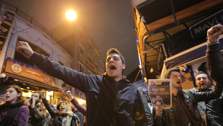 Protestors shout and raise their fists.