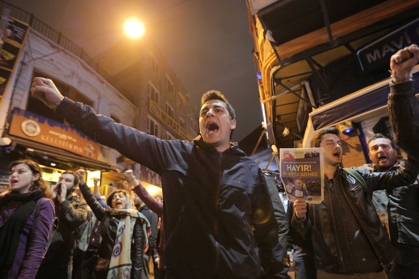 Protestors shout and raise their fists.