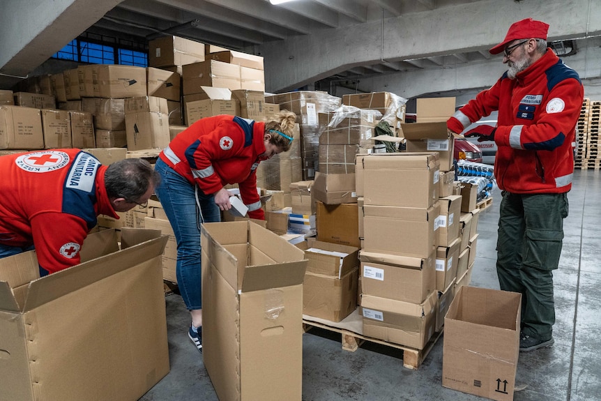 People wearing Red Cross uniforms pack boxes.