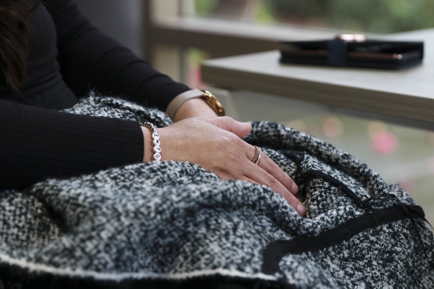 A woman's hands with a ring, bracelet and watch on her lap