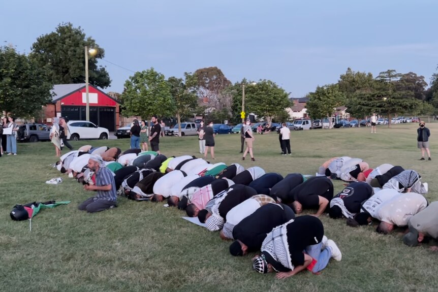 group of people praying on the grass