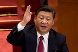 China's President Xi Jinping speaking with raised hand 