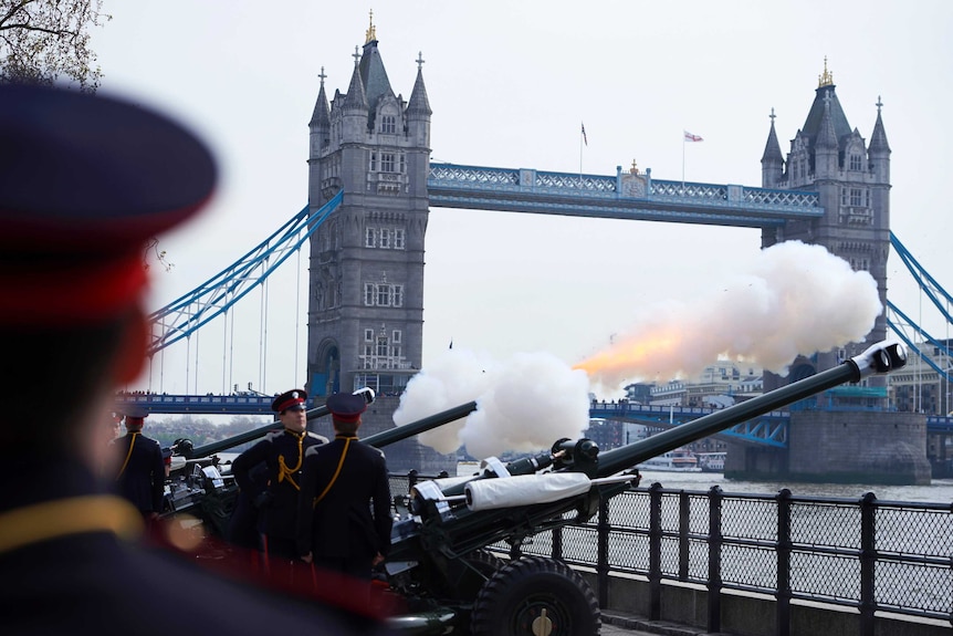 Soldiers fire a 62 gun salute against a backdrop of London's Tower Bridge.