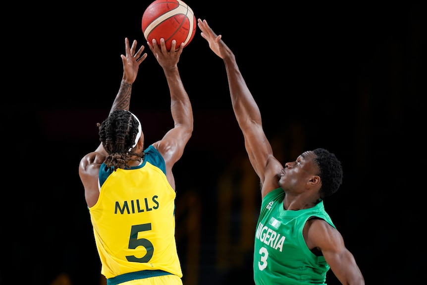 Nigeria's Caleb Agada tries to block a shot by Australia's Patty Mills at the Tokyo Olympics.
