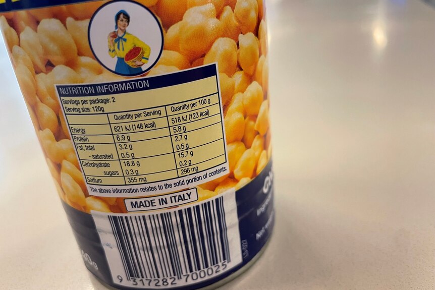 The nutritional information panel on the back of a tin of chickpeas on a white bench top. 