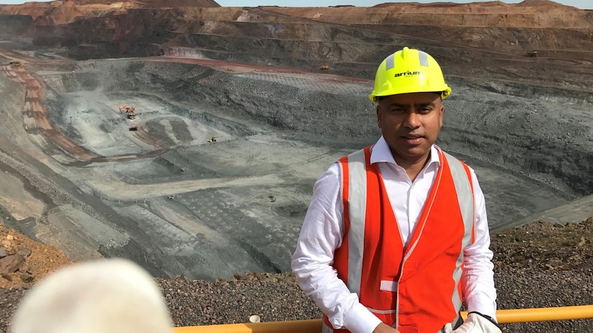 A man wearing a high vis vest and hard hat stands in front of a mind site