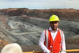 A man wearing a high vis vest and hard hat stands in front of a mind site