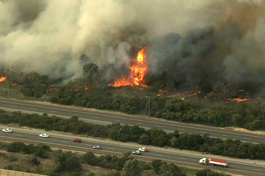 An aerial shot of a bushfire near a big road.