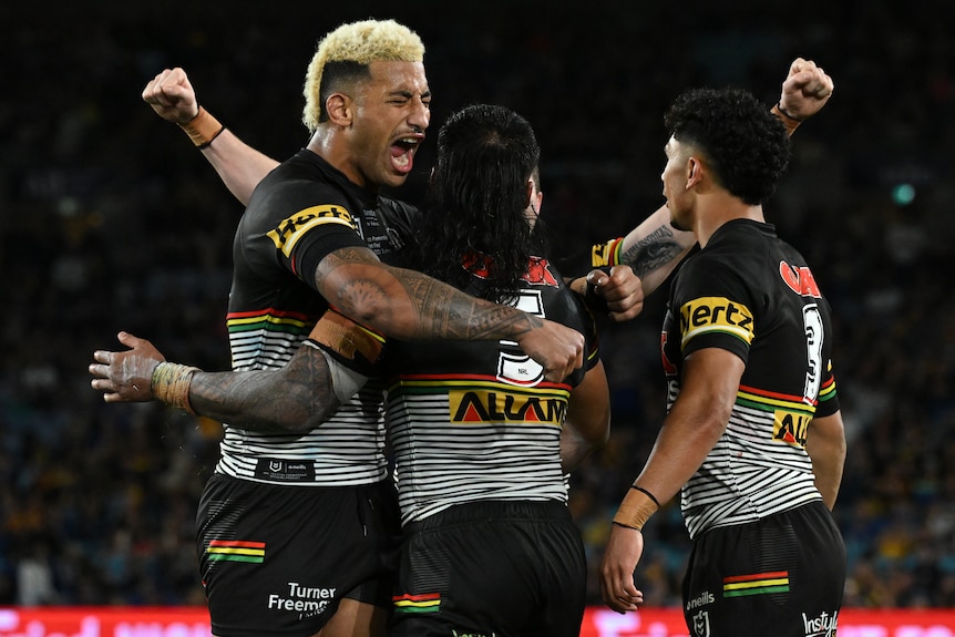 Four Penrith NRL players embrace as they celebrate winning the grand final.