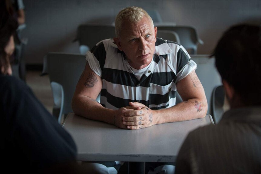 Still image of Daniel Craig wearing a black and white striped prison jumpsuit in 2017 film Logan Lucky.