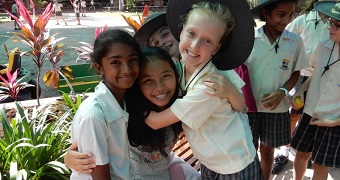 Children of different nationalities hug in a school playground.