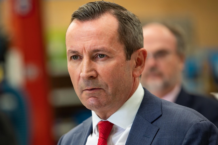 Premier Mark McGowan wearing a blue suit and red tie gives a stern look.