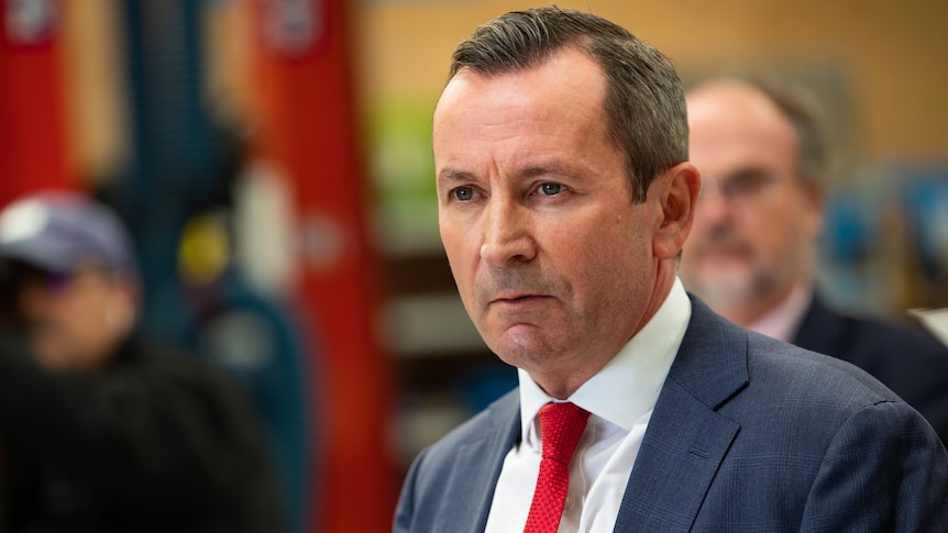Premier Mark McGowan wearing a blue suit and red tie gives a stern look.