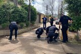 Police officers search outside a home