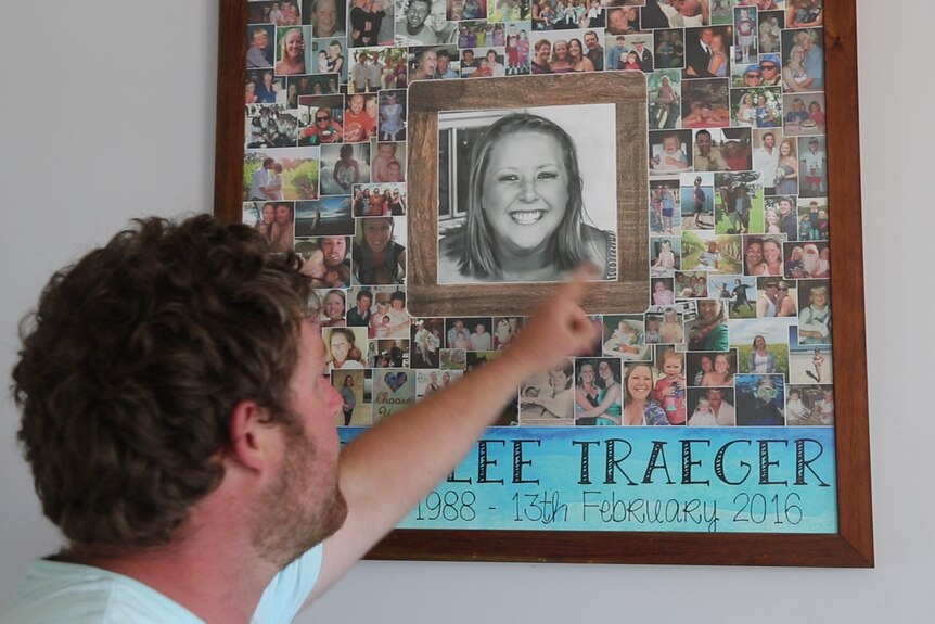 Man facing away from camera pointing at photo collage on wall