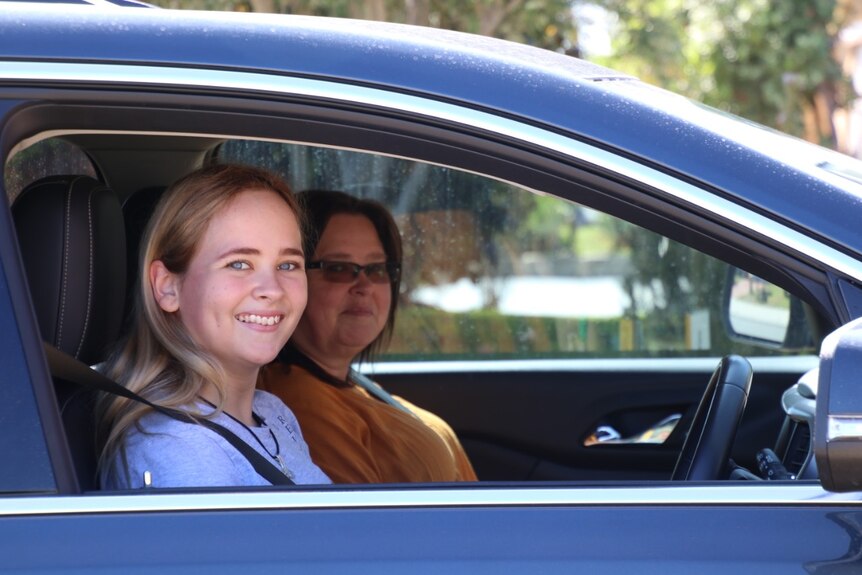 Amy Carter sits behind the wheel of a car.