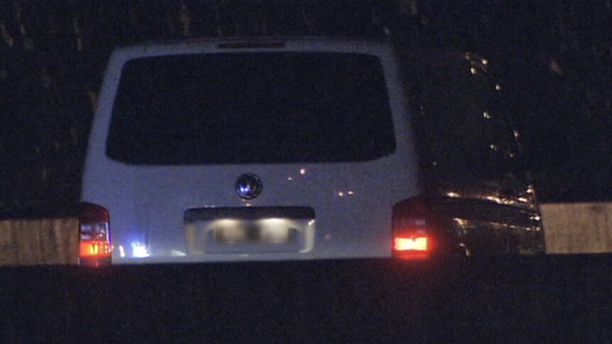 A white van sits stationary in a right-hand lane of the tollway, at night.