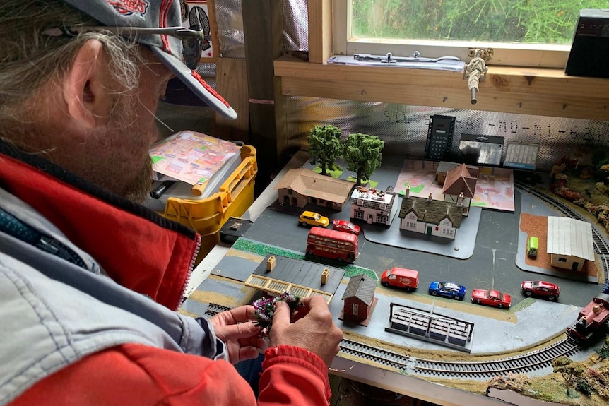 Hobby carpenter works on intricate wooden town and railway for a Christmas window display.