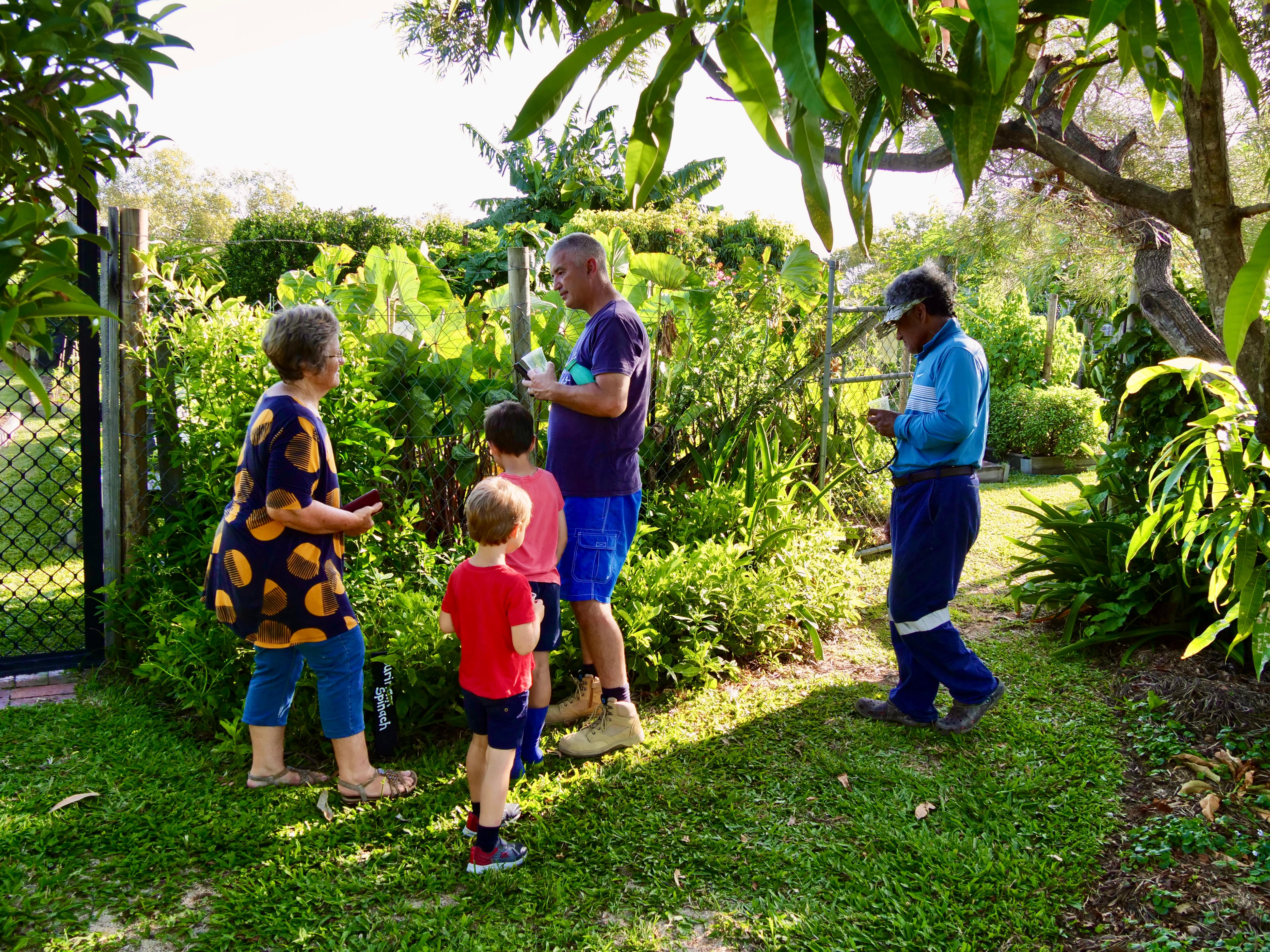 Un grupo de cinco personas caminan por un jardín verde y conversan.