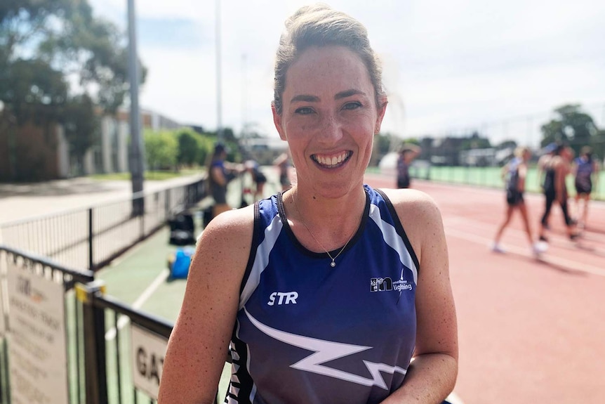 Profile shot of Elissa Kent standing in front of sporting track.