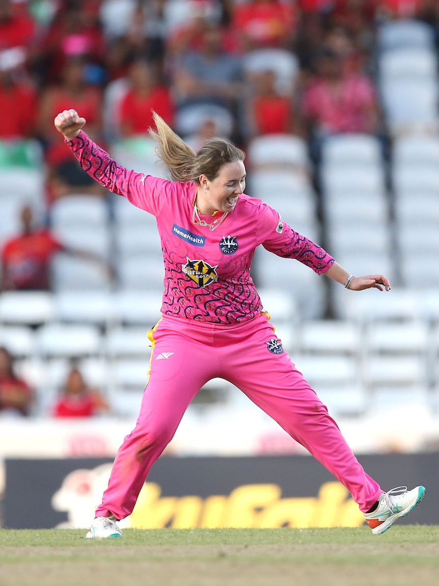 Wellington winds up her right arm as she celebrates wicket, wearing a pink cricket uniform