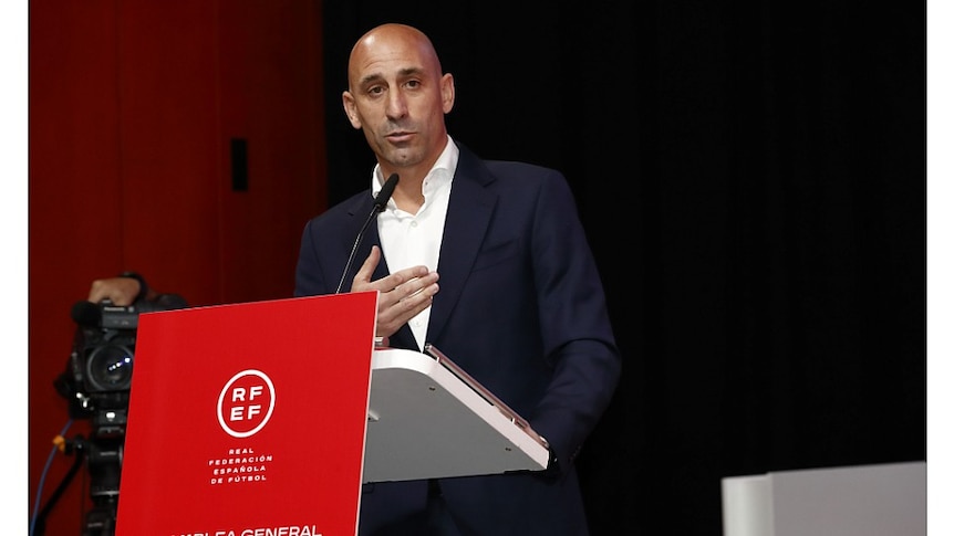  Luis Rubiales standing at a lectern, talking into a microphone