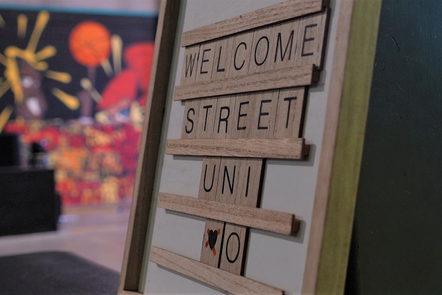 A wooden sign reads 'Welcome Street Uni'.