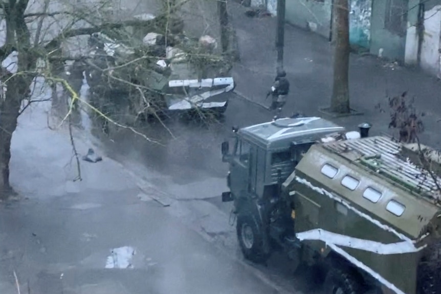 A military truck and tank are seen on a street of Kherson