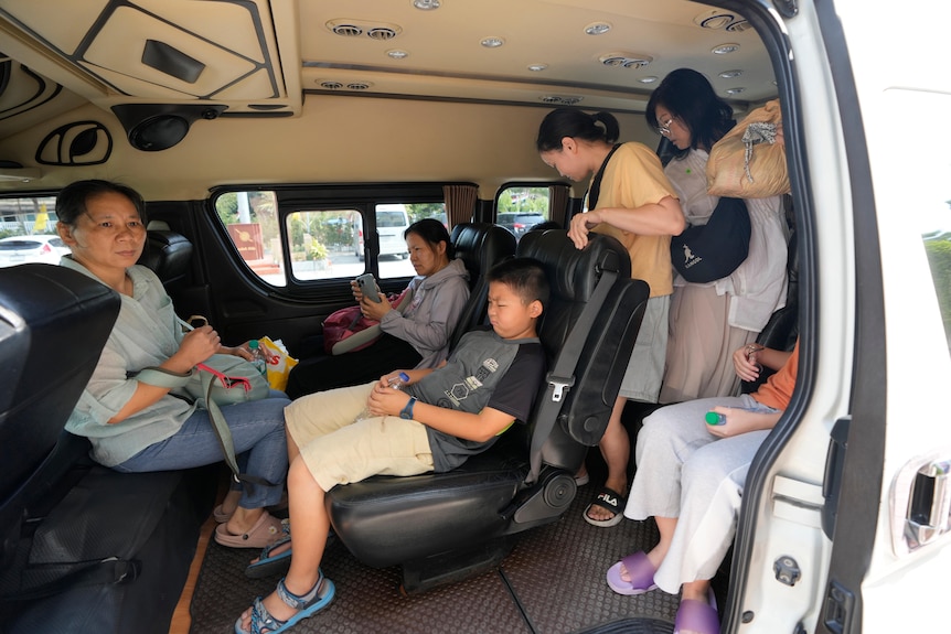 Chinese women and children pictured sidling in to a white van. One woman has a concerned look on her face.