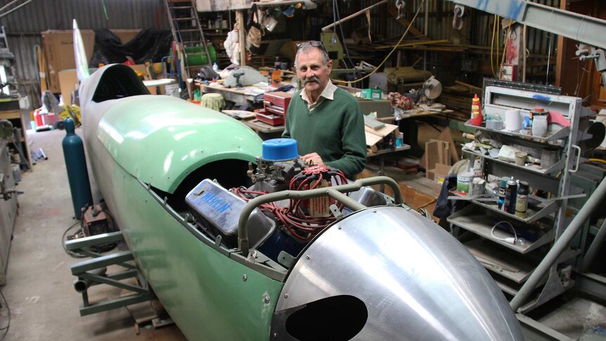 Rod McNeill stands at the side of the spitfire aeroplane he is constructing.