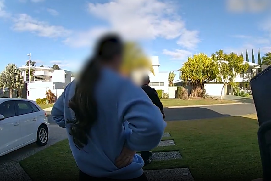 An image of a woman with her face blurred walking out of a Gold Coast house with police