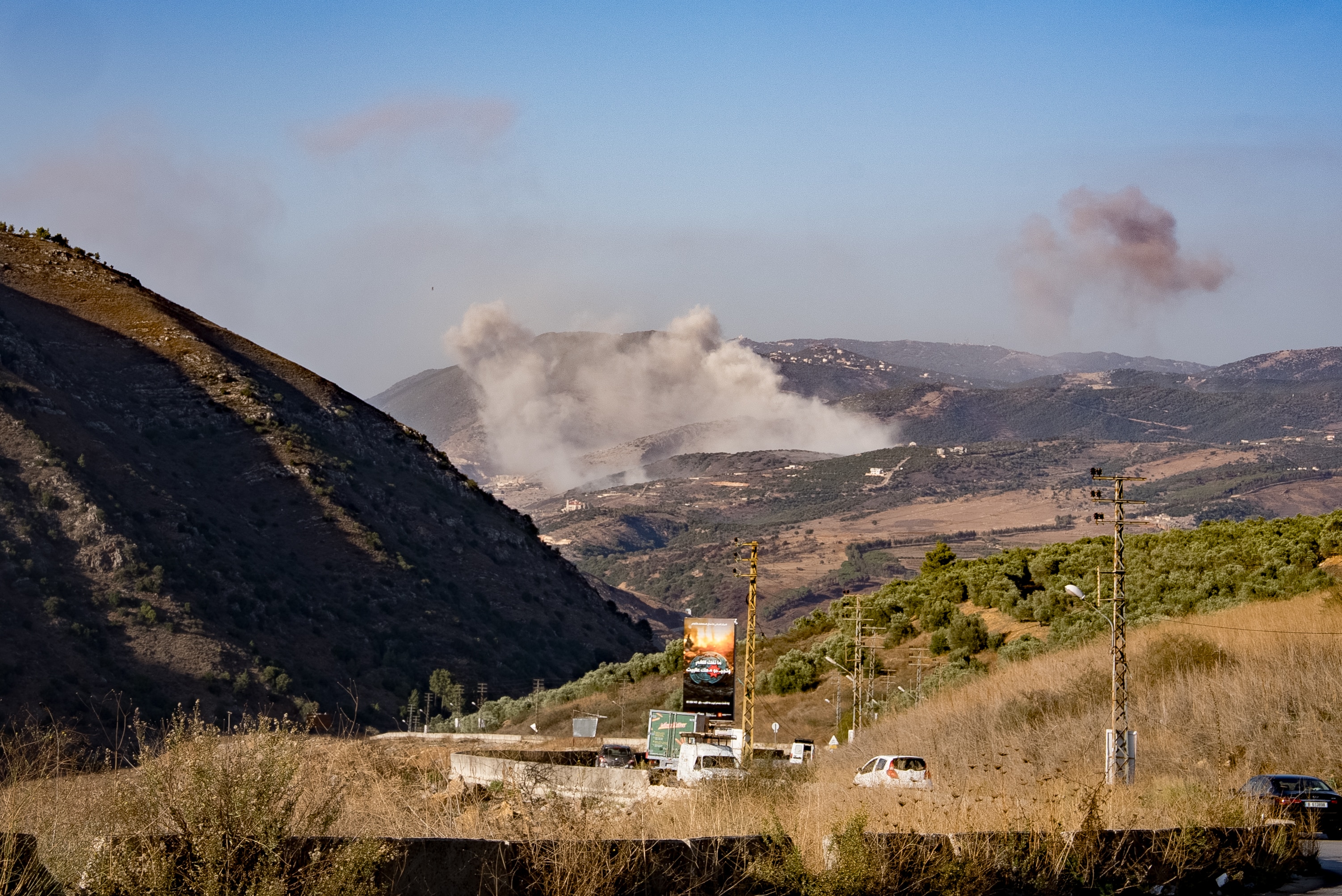 Smoke billowing from a distant location near mountains after an airstrike.