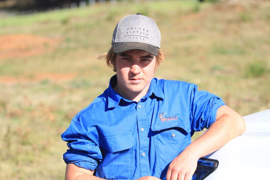 Mitchell Steel, a 17-year-old with sandy blonde hair and wearing a hat, in a paddock in the sunshine.