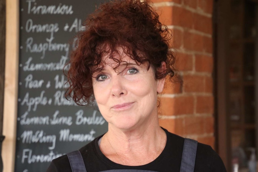 A woman with red curly hair in front of a menu board