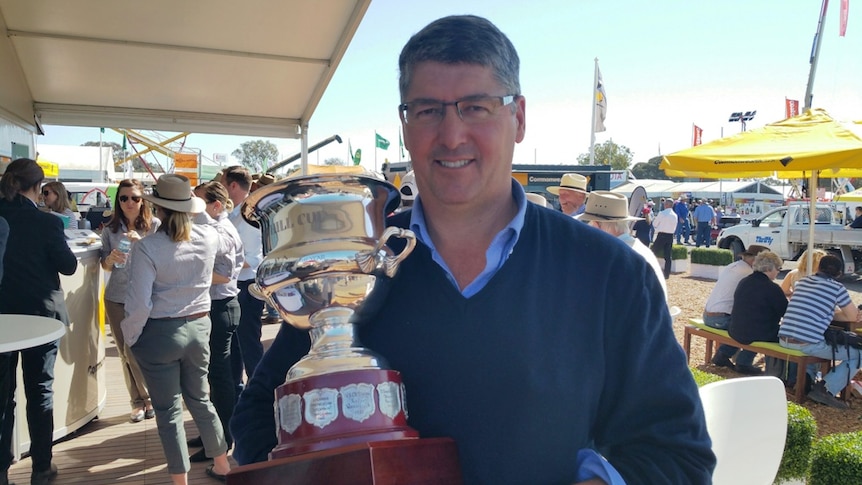 Breeza cotton and grain farmer John Hamparsum holding the Brownhill Cup at Agquip with the crowds in the background.