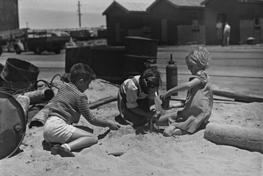 Three children from the Italian ship Gerusalemme playing in sand on the docks at Fremantle, 4 December 1945.