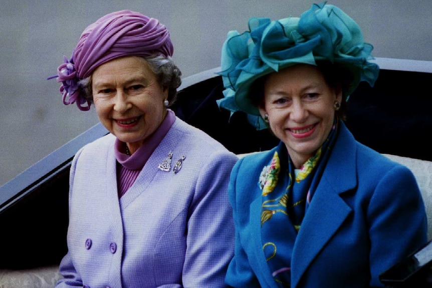 Queen Elizabeth II and Princess Margaret travel in an open carriage.