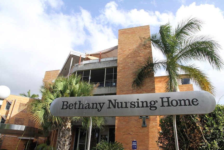 A metal sign that says 'Bethany Nursing Home' is in front of a tall brown brick building.