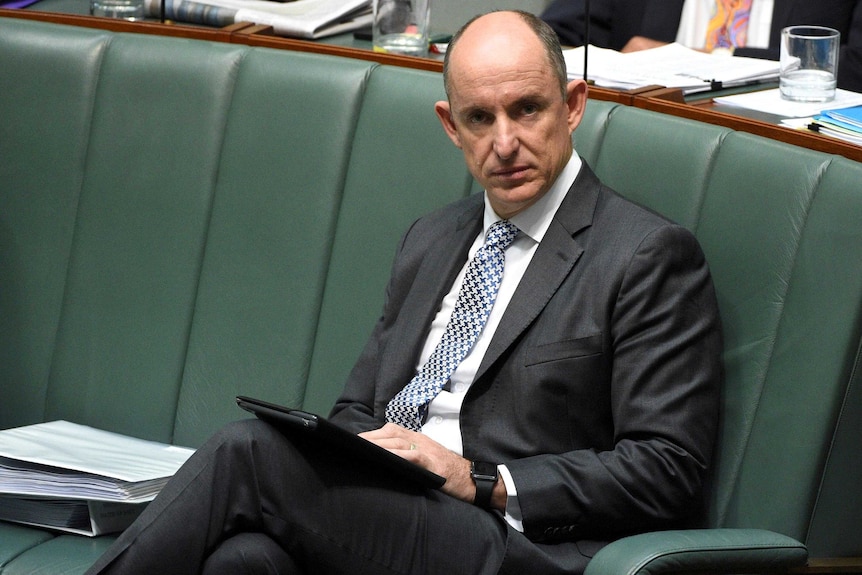 Stuart Robert looks down the lens of the camera while sitting in the House of Representatives chamber.